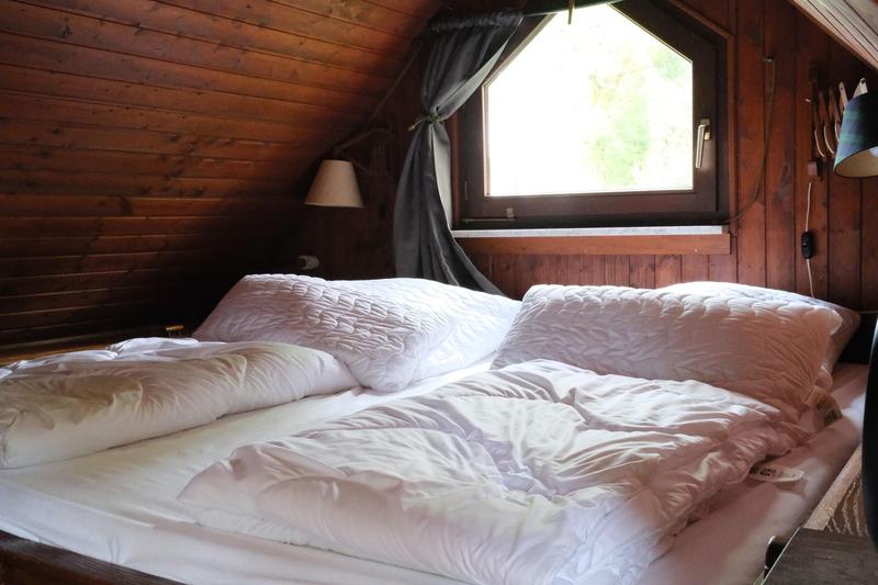 Zimmer 2: breites Kingsize-Bett unter der holzverkleideten Dachschräge, Giebelfenster ins Grüne